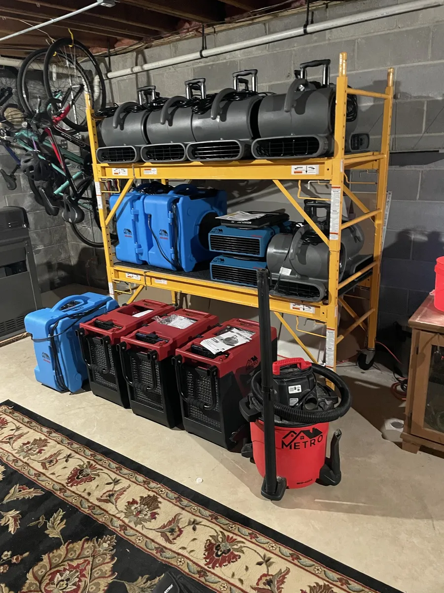 Metro Home Improvement air movers, dehumidifiers, air scrubbers and shop vac staged on a rack