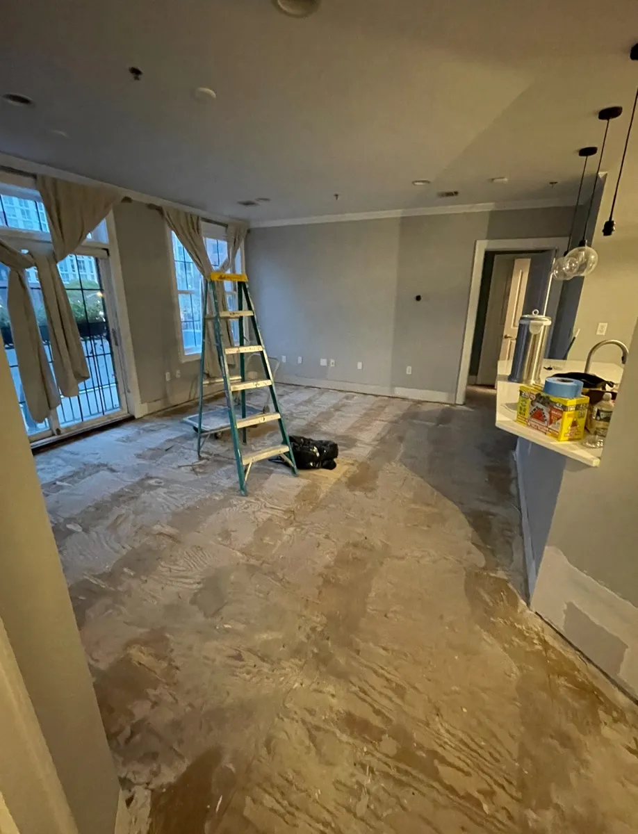 Apartment mid-rebuild during a water damage claim, flooring removed and a ladder in place