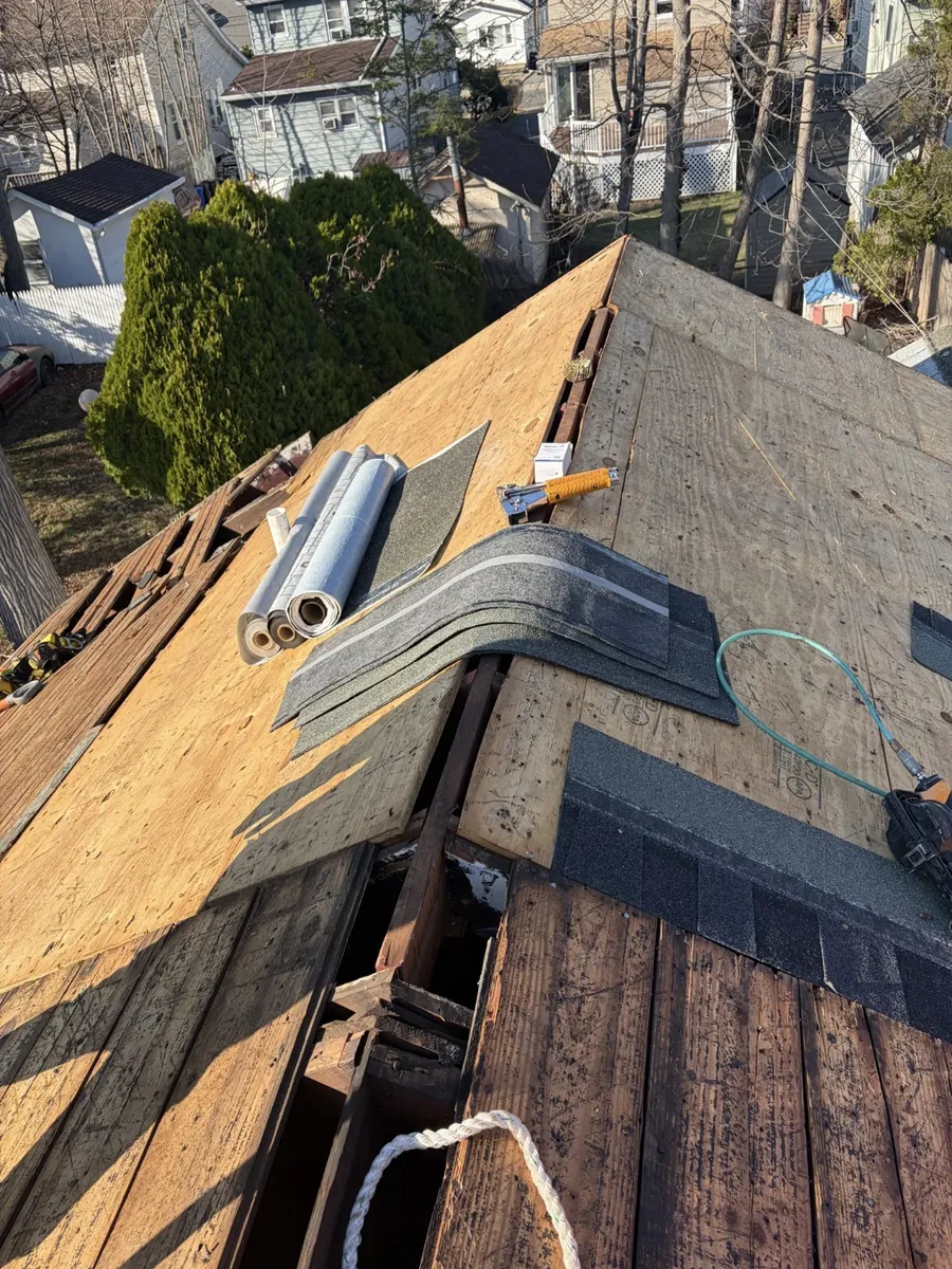 Roof tear-off in progress on a North Jersey home, with new sheathing and bundles of shingles on the ridge